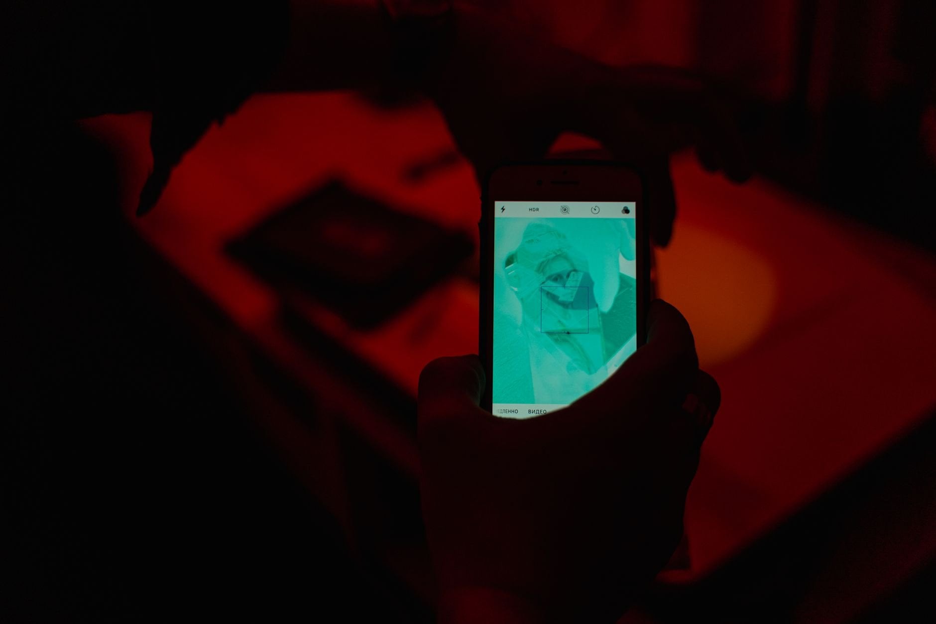 Close-up of hands using a smartphone camera in a low-light setting